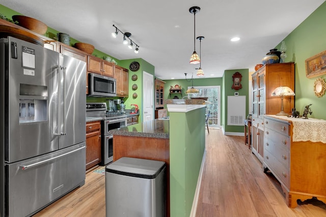 kitchen with decorative light fixtures, a kitchen island, light hardwood / wood-style floors, and appliances with stainless steel finishes