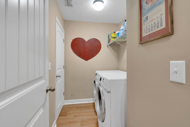 washroom with washer and clothes dryer, light hardwood / wood-style floors, and a textured ceiling