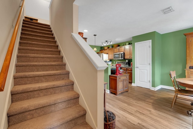 staircase with track lighting and wood-type flooring