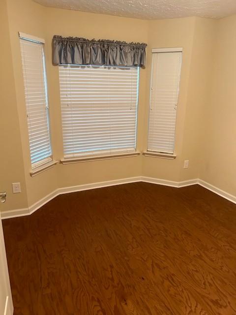 empty room with dark hardwood / wood-style floors and a textured ceiling