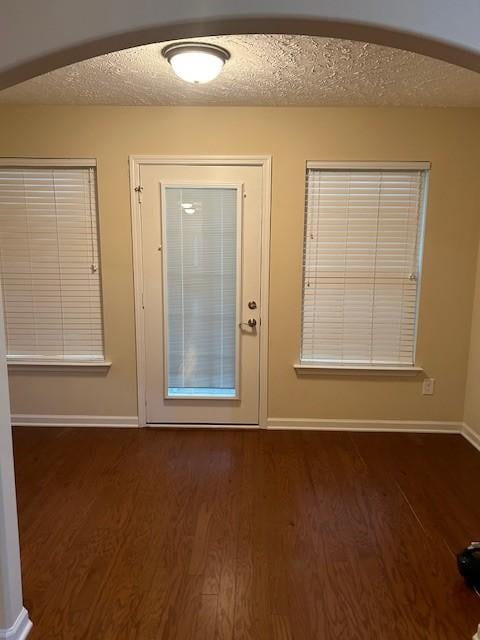 doorway to outside with dark hardwood / wood-style floors and a textured ceiling