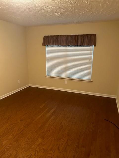 unfurnished room with dark hardwood / wood-style floors and a textured ceiling