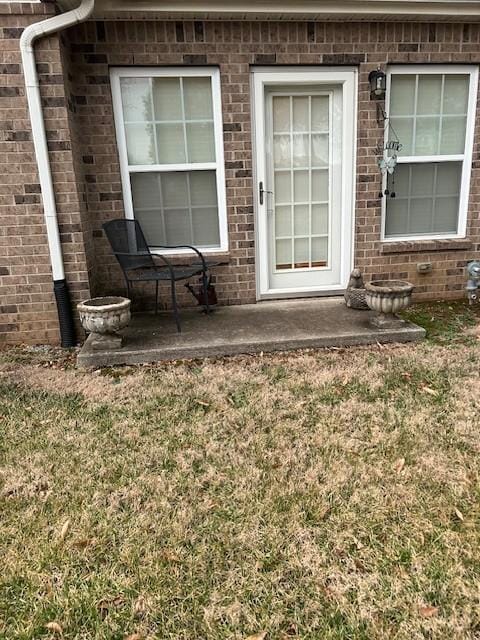 entrance to property with a patio and a yard