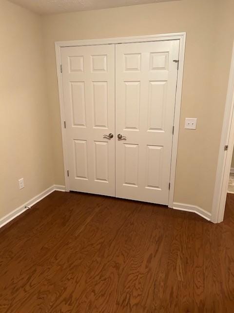 unfurnished bedroom with dark hardwood / wood-style flooring and a closet