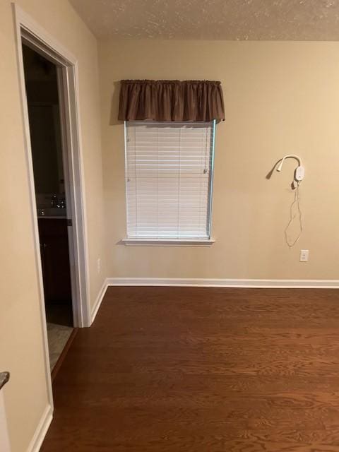 spare room featuring dark hardwood / wood-style flooring and a textured ceiling