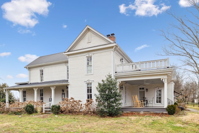 rear view of property featuring a porch, a yard, and a balcony