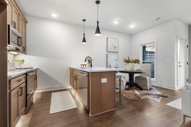 kitchen featuring a kitchen bar, sink, appliances with stainless steel finishes, kitchen peninsula, and pendant lighting