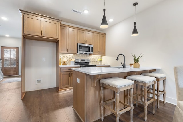 kitchen featuring sink, hanging light fixtures, backsplash, stainless steel appliances, and dark hardwood / wood-style floors