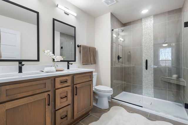 bathroom with vanity, toilet, tile patterned floors, and a shower with shower door