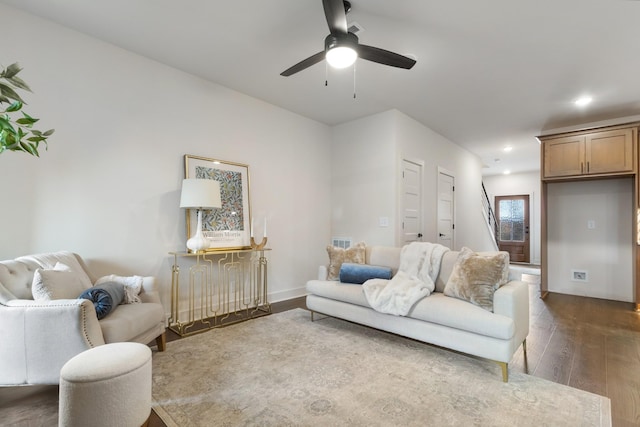 living room featuring dark wood-type flooring and ceiling fan