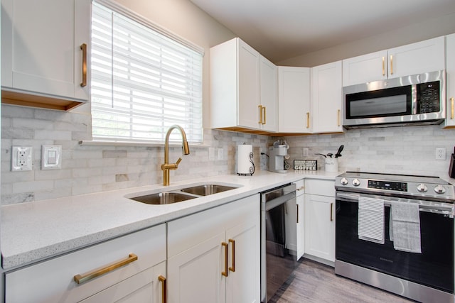 kitchen with sink, white cabinetry, tasteful backsplash, stainless steel appliances, and hardwood / wood-style floors