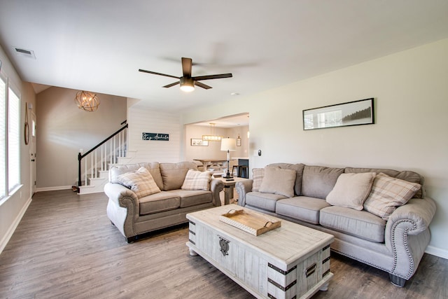 living room with ceiling fan with notable chandelier and hardwood / wood-style floors