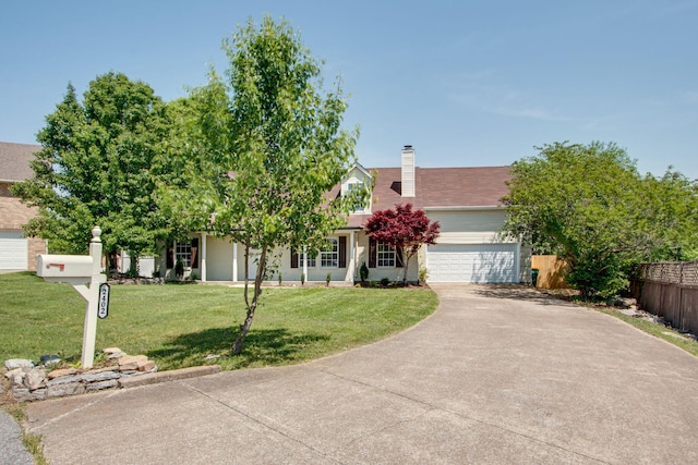 view of property hidden behind natural elements featuring a garage and a front yard