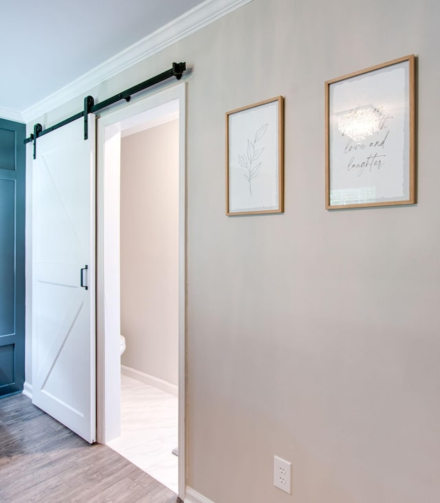 corridor with crown molding, a barn door, and light wood-type flooring