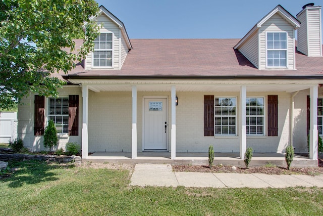 cape cod home with a front yard and covered porch