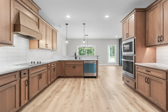 kitchen featuring pendant lighting, light hardwood / wood-style flooring, appliances with stainless steel finishes, backsplash, and custom range hood