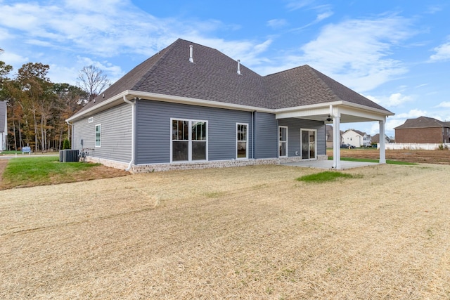 rear view of house with central AC, a patio area, and a lawn