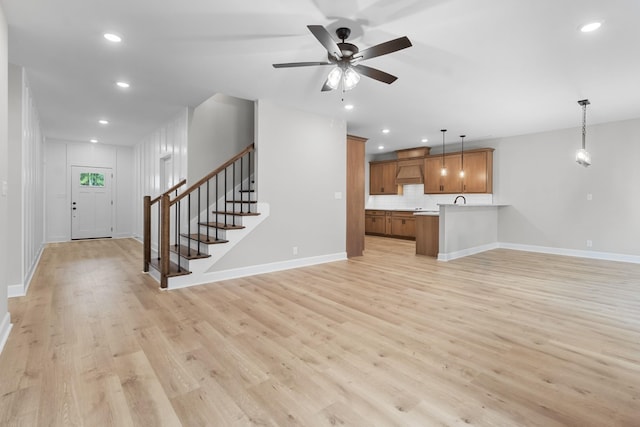 unfurnished living room featuring ceiling fan and light wood-type flooring