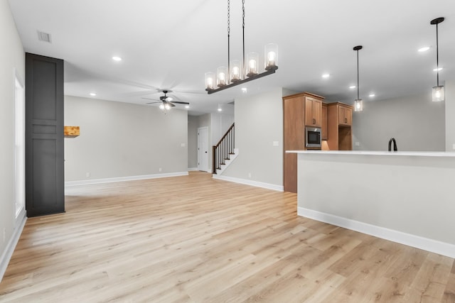 unfurnished living room featuring ceiling fan, sink, and light hardwood / wood-style floors