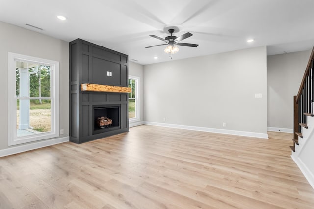 unfurnished living room featuring ceiling fan, a fireplace, and light wood-type flooring