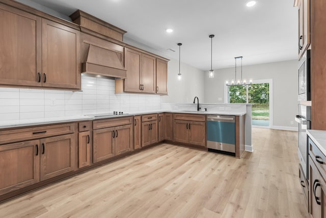 kitchen with sink, custom exhaust hood, hanging light fixtures, appliances with stainless steel finishes, and decorative backsplash