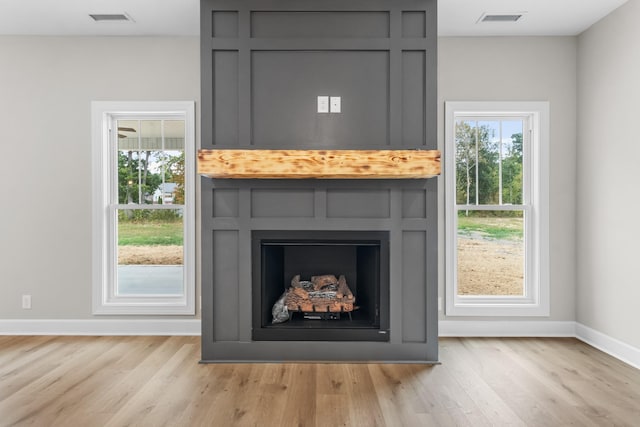 interior details featuring wood-type flooring and a large fireplace