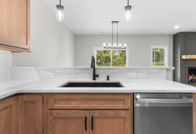 kitchen with pendant lighting, sink, stainless steel dishwasher, and backsplash