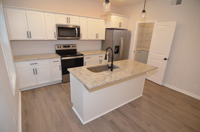 kitchen with white cabinetry, sink, hanging light fixtures, stainless steel appliances, and a center island with sink