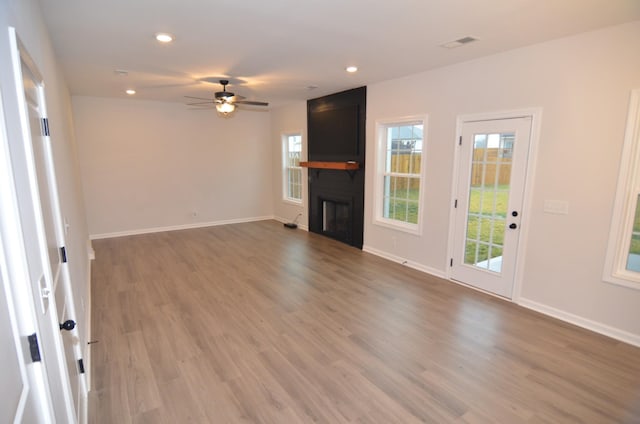 unfurnished living room featuring ceiling fan, a fireplace, and wood-type flooring