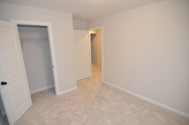 unfurnished bedroom with light colored carpet and a closet