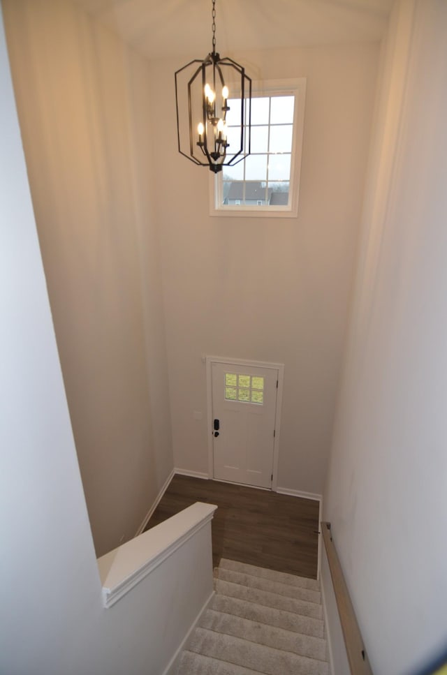 staircase featuring an inviting chandelier, a healthy amount of sunlight, and hardwood / wood-style floors