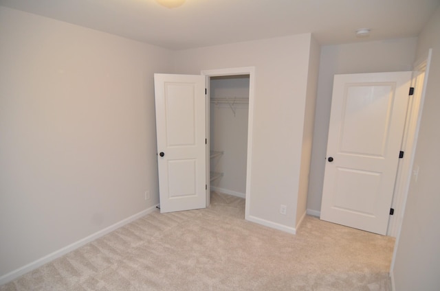 unfurnished bedroom with light carpet, a spacious closet, and a closet