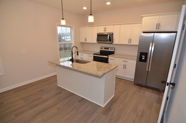 kitchen with sink, white cabinetry, hanging light fixtures, stainless steel appliances, and a center island with sink