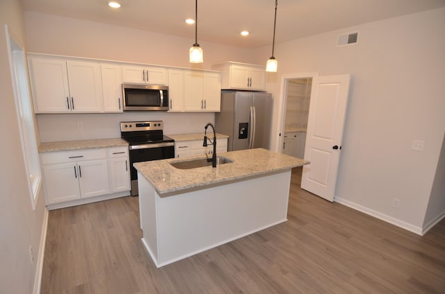 kitchen featuring decorative light fixtures, sink, white cabinets, a kitchen island with sink, and stainless steel appliances