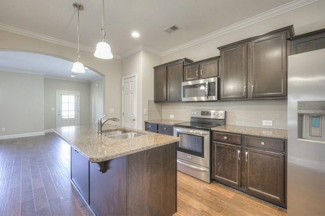 kitchen with sink, appliances with stainless steel finishes, dark brown cabinets, an island with sink, and decorative light fixtures