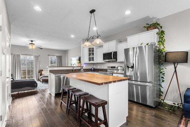 kitchen featuring butcher block countertops, a breakfast bar area, white cabinetry, pendant lighting, and stainless steel appliances