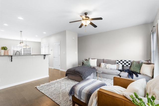 living room with dark hardwood / wood-style flooring and ceiling fan with notable chandelier