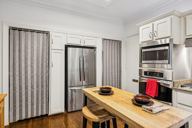 kitchen with crown molding, light stone counters, appliances with stainless steel finishes, dark hardwood / wood-style floors, and white cabinets