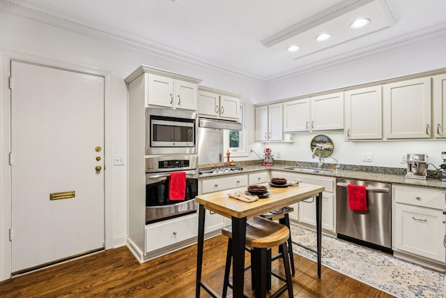 kitchen featuring appliances with stainless steel finishes, dark hardwood / wood-style flooring, light stone countertops, and white cabinets