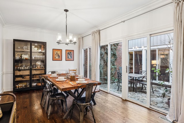 dining space featuring ornamental molding, a healthy amount of sunlight, dark wood-type flooring, and an inviting chandelier