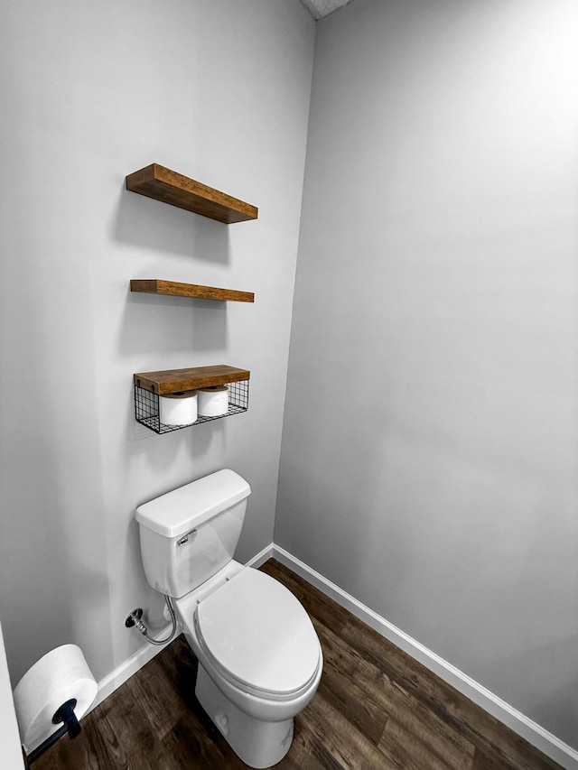 half bath featuring toilet, baseboards, and wood finished floors