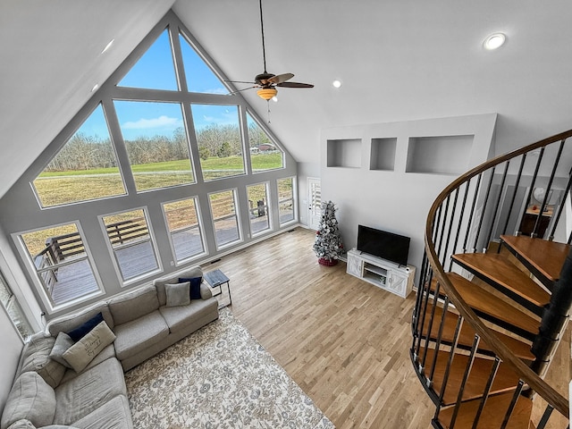 living area with ceiling fan, stairway, wood finished floors, high vaulted ceiling, and recessed lighting