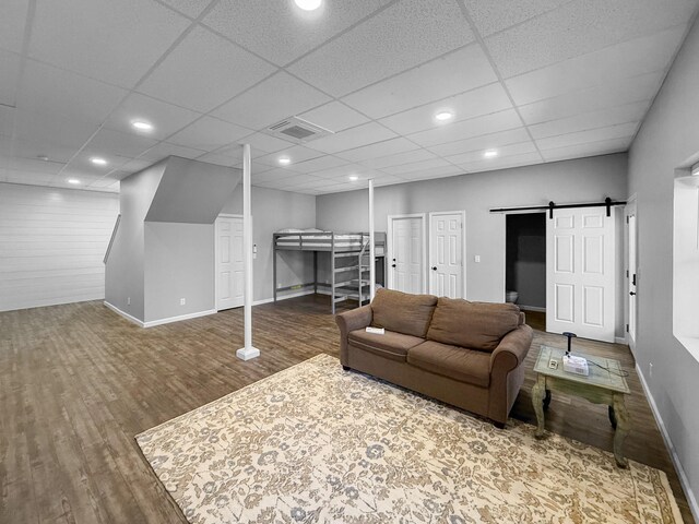 living area featuring a barn door, wood finished floors, visible vents, and baseboards