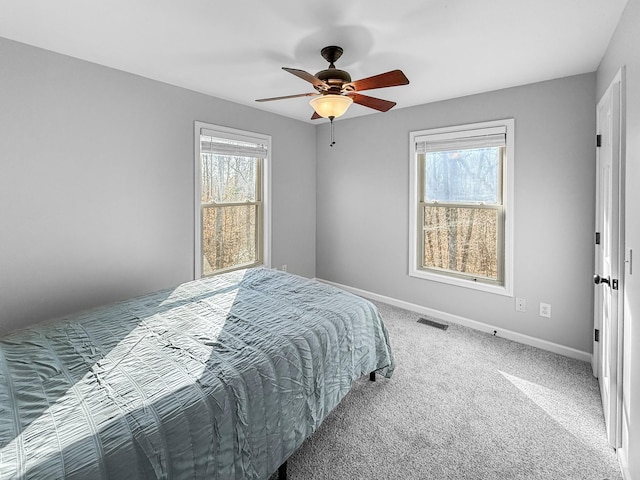 carpeted bedroom with visible vents, ceiling fan, baseboards, and multiple windows