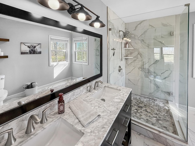 bathroom with double vanity, marble finish floor, a marble finish shower, and a sink