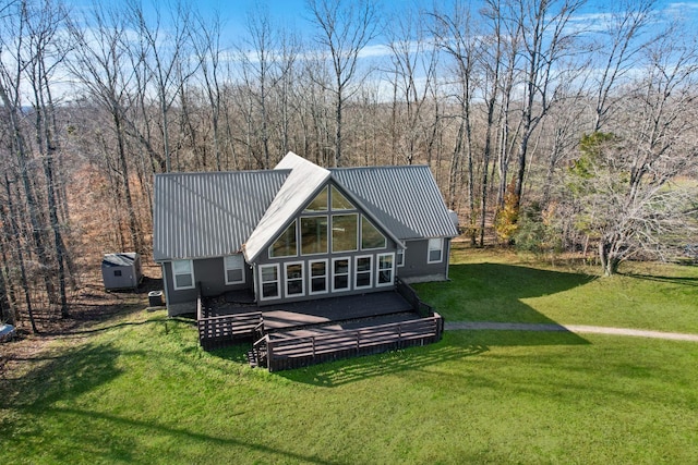 rear view of property with a wooden deck, metal roof, and a yard