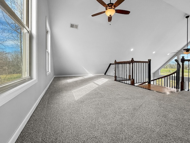 carpeted empty room with ceiling fan, high vaulted ceiling, visible vents, and baseboards