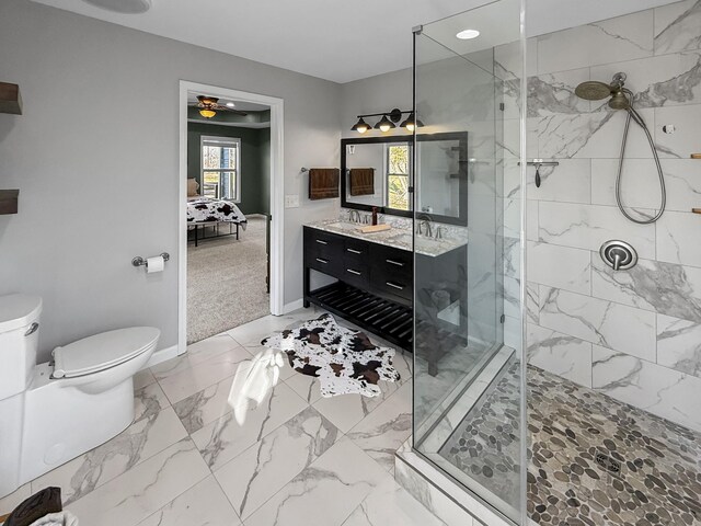 ensuite bathroom featuring toilet, connected bathroom, vanity, tiled shower, and baseboards