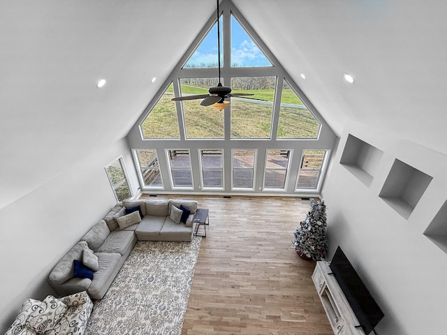 living area featuring high vaulted ceiling, light wood-type flooring, and a ceiling fan