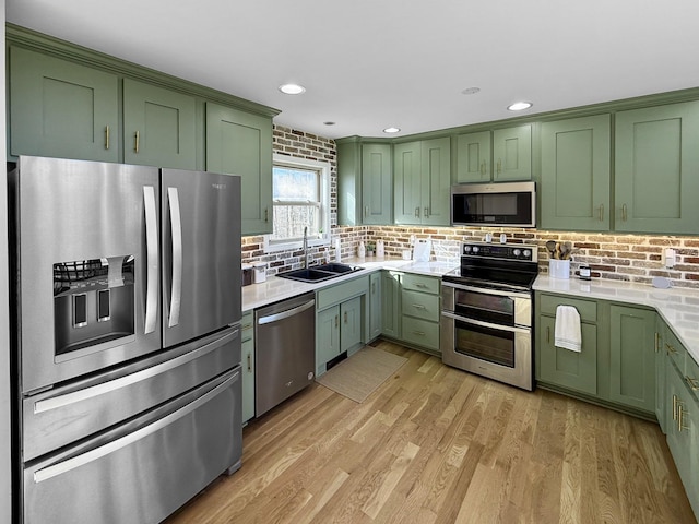 kitchen featuring green cabinets, light countertops, appliances with stainless steel finishes, and a sink